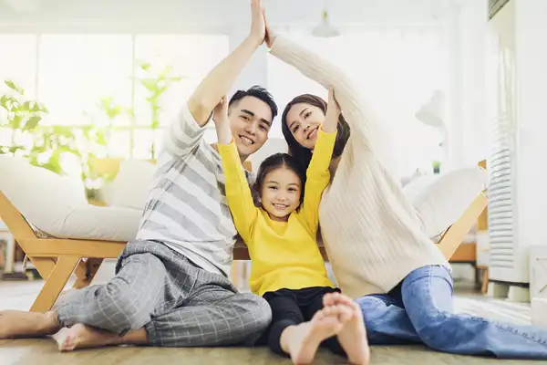 Happy family forming house roof with their hands at home