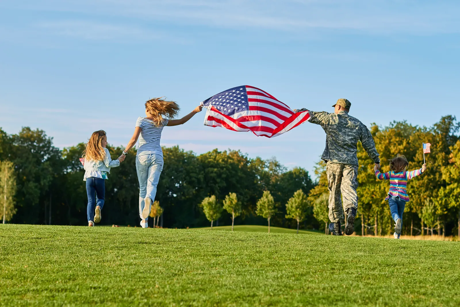 A military family standing together with an American flag outdoors