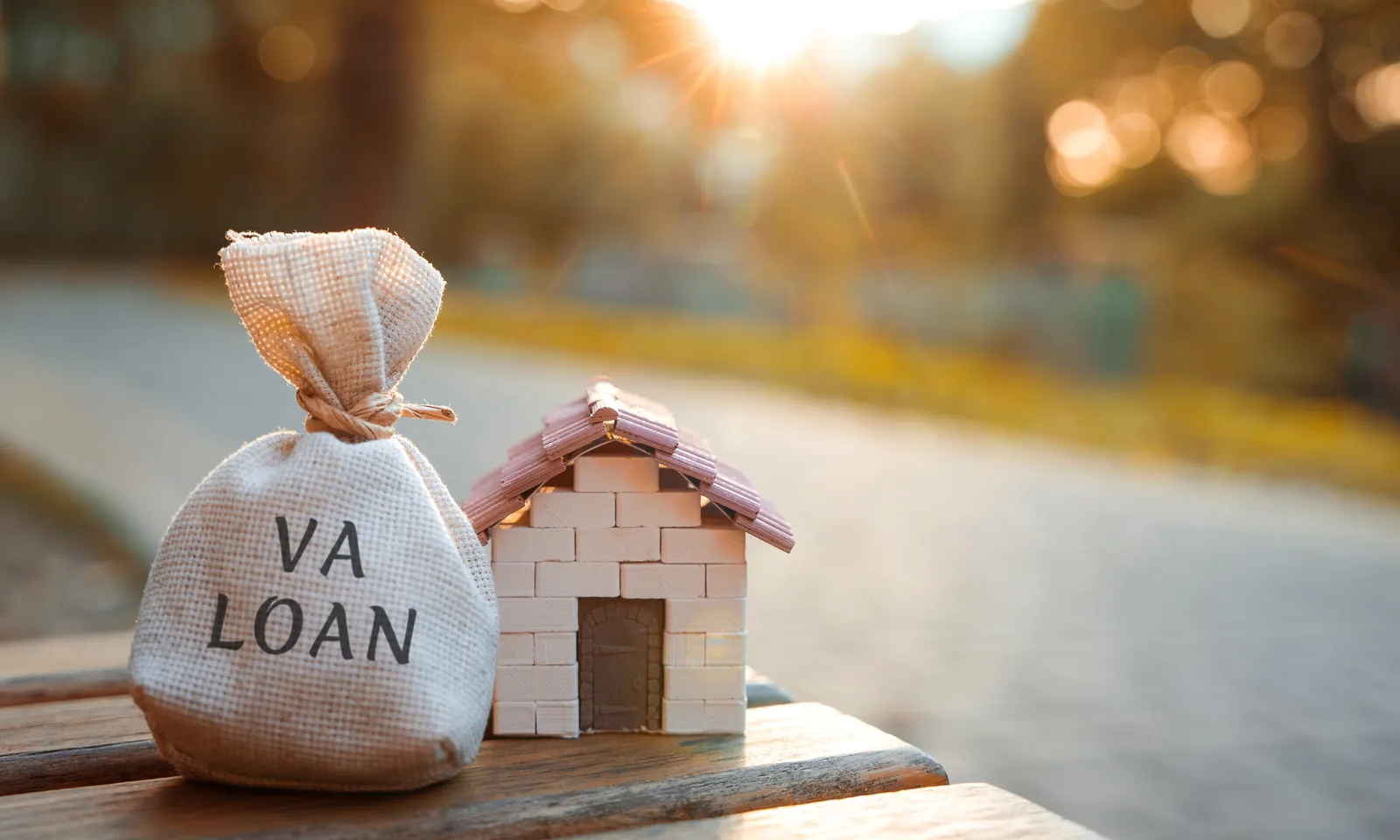 VA loan calculator estimate next to a brick home and savings bag